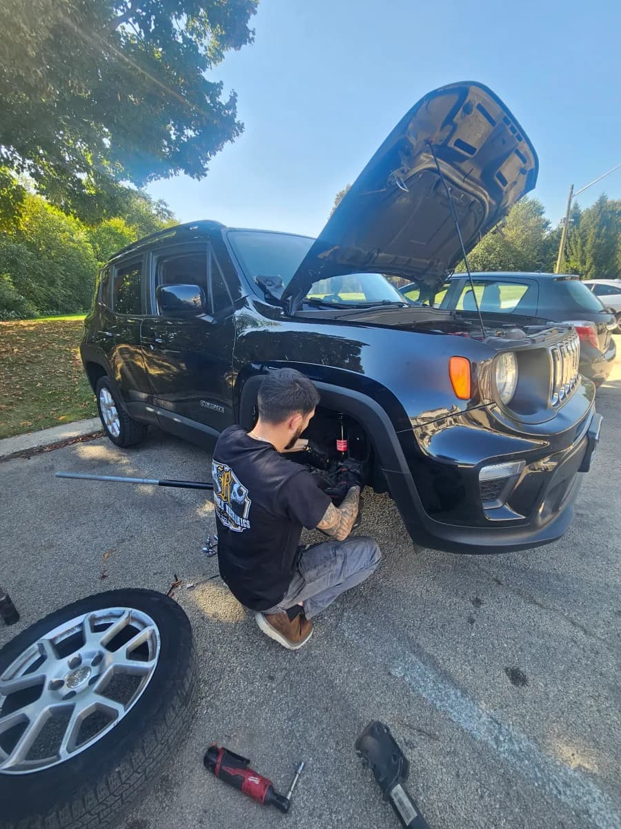 Rico, owner of R's Mobile Mechanics, doing a brake job on a Jeep in Rockford